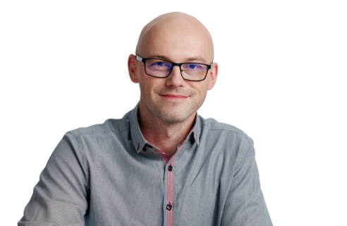 Portret Jakuba Wachola, back-end developera i autora artykułów. Zdjęcie przedstawia go uśmiechniętego, w okularach, o profesjonalnym i przyjaznym wyglądzie, na białym tle.