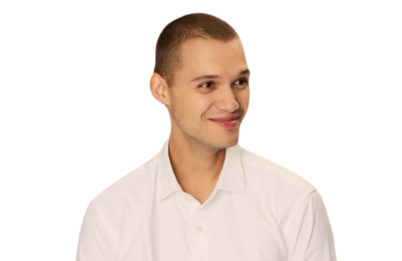 Zdjęcie autora artykułu, specjalisty ds. marketingu w Primotly. Przyjazny młody mężczyzna z krótko przyciętymi włosami i białą koszulą zapinaną na guziki, uśmiechający się subtelnie na jednolitym tle.