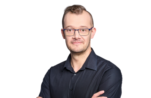 Image of Marek Krokwa, confidently posing with arms crossed. He's CTO at Primotly and contributor to our insightful technology articles. Marek is wearing a dark collared shirt and glasses, presenting a smart and approachable look, set against a clean white background